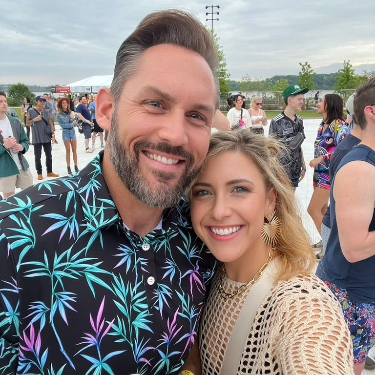 Rachelle and Clayton smiling at an outdoor celebration